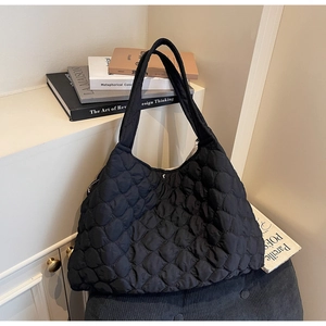 Macro detail of black quilted tote bag with diamond stitching on a display shelf