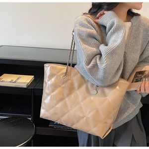 Detail of warm beige quilted tote bag with metallic chain strap and glossy leather finish