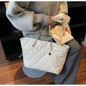 Detail of quilted tote bag with silver chain strap and shiny faux leather texture