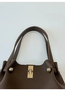 Detail of dark brown lychee pattern leather handbag with gold metal twist lock buckle