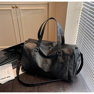 Détail du sac de sport en cuir noir texturé avec poignées et bandoulière réglable