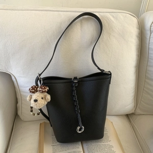Close-up of black leather bucket bag with silver ring detail and plush bear charm