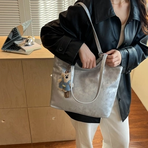 Detail of silver textured tote bag with Fashion & Bags logo and cute bear pendant charm