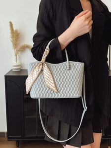 Bolso de mano azul claro acolchado con pañuelo de seda, usado como bandolera chic