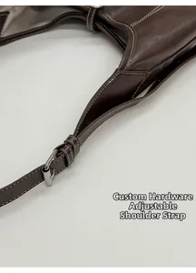 Close-up of dark brown leather tote with white contrast stitching and adjustable buckle