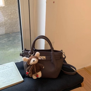 Close-up of retro dark brown leather bucket bag with metal buckle and teddy bear charm