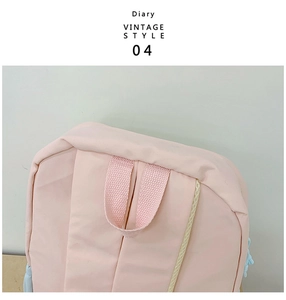 Detail view of pink canvas backpack with cream mesh trim and vintage diary branding