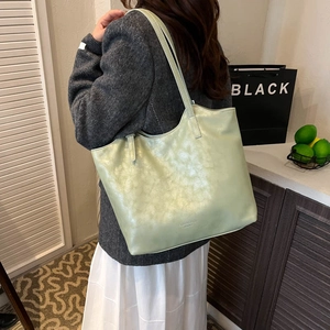 Detail of light green faux leather tote bag showing large capacity and soft texture