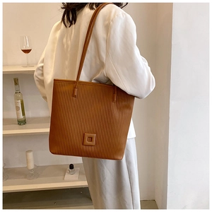 Détail du sac fourre-tout marron caramel avec texture plissée verticale et boucle carrée