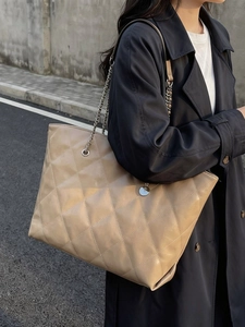 Quilted khaki tote bag with chain strap shown on model in stylish outdoor setting