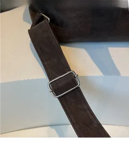 Detail of adjustable silver buckle on dark brown leather shoulder strap with matte texture