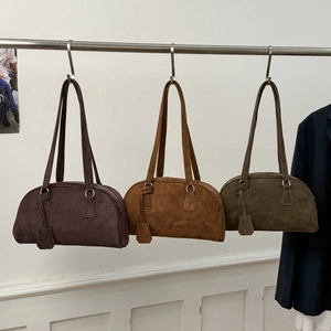 Suede Boston bags in brown, caramel, and olive green shown hanging in a studio setting