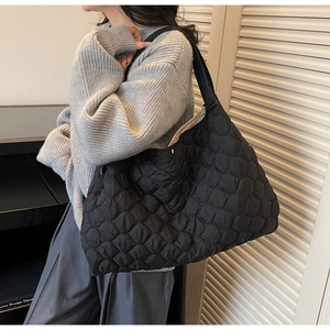 Detailed view of black quilted tote bag worn on shoulder for stylish daily commuting