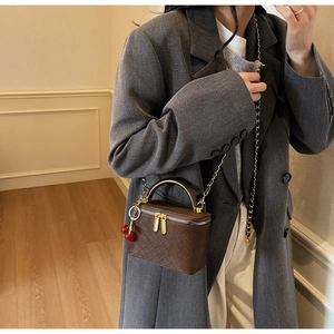 Detail of dark brown woven leather box bag with gold handle shown on fashion model