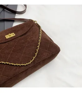 Detail der dunkelbraunen Stepptasche aus Wildleder mit Goldschloss und Kettenriemen