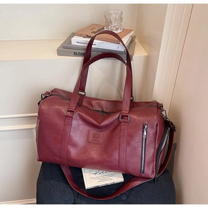 Détail du sac de sport en cuir bordeaux avec compartiment chaussures et poche zippée