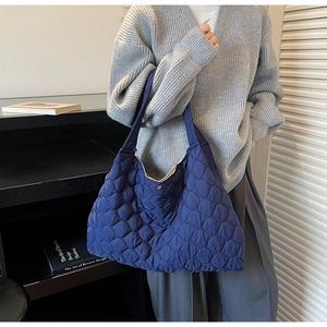 Detail of navy blue quilted tote bag showing padded texture and metallic magnetic snap