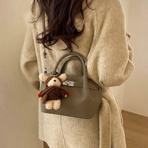 Detail of khaki leather bucket bag with silver rotating lock and bear charm