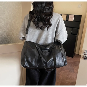 Détail du sac de sport en similicuir noir avec poignées et bandoulière amovible