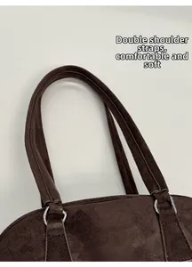 Close-up of double shoulder straps with silver metal rings on dark brown suede Boston bag