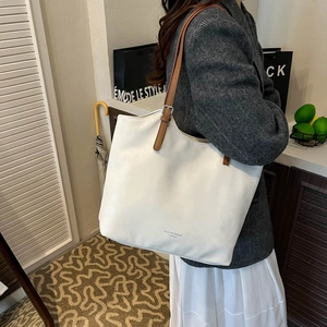 Detailed view of a white PU leather tote bag with brown straps worn on the shoulder