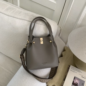 Detail of grey-brown bucket bag with gold hardware and geometric knit strap