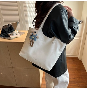 Close-up of a white tote bag with bear charm and Fashion & Bags Leather text detail