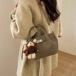 Detail of khaki bucket bag with lychee texture, silver twist lock and plush bear charm