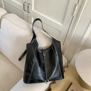 Detail of a large black tote bag featuring contrast white stitching and metal ring buckle