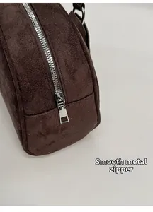 Detail of silver smooth zipper and stitching on a dark brown suede bowling shoulder bag