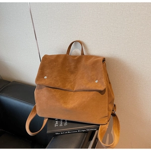 Detail view of brown faux suede backpack featuring flap closure and silver buckle hardware