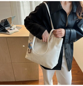 Detail of white PU leather tote bag with cute bear charm in a modern office workspace