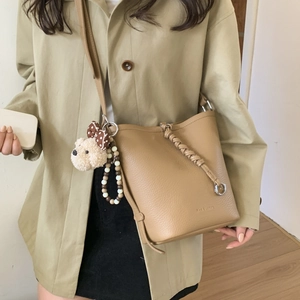 Detailed shot of dark apricot leather bucket bag with textured finish and charms