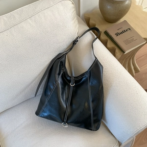 Detail of black tote bag showing white contrast stitching and silver hardware accents