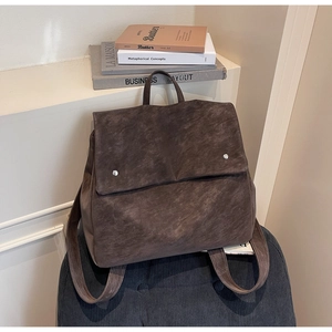 Detail of dark brown vintage faux suede backpack with flap and silver buckles