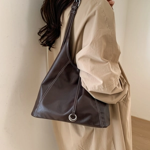 Detail of dark brown tote bag featuring white contrast stitching and silver metal ring