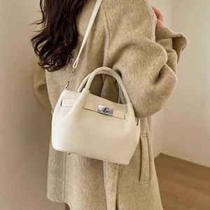 Detail of off-white bucket bag with silver turn-lock and lychee grain leather texture