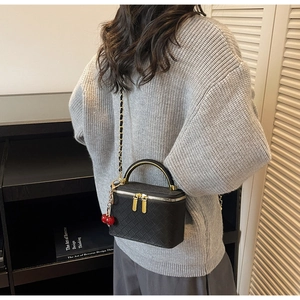 Fashionable black woven vanity case bag with gold chain and cherry pendant detail
