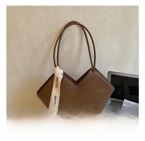 Detail of dark brown woven tote bag featuring a V-shaped opening and decorative ribbon
