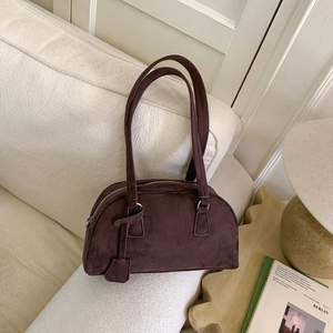Close-up of a vintage dark brown suede Boston bag on a cozy sofa in a home setting