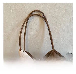 Detailed close-up of brown woven tote bag handles with decorative logo ribbon strap