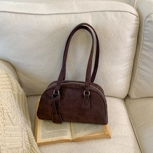Detail view of deep brown frosted leather Boston bag with silver zipper on vintage books
