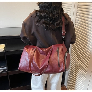 Détail du sac de sport en cuir bordeaux montrant la texture et la bandoulière réglable