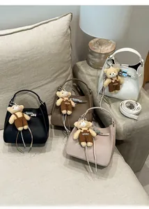 Detail view of four lychee texture bucket bags with metal locks and cute bear charms