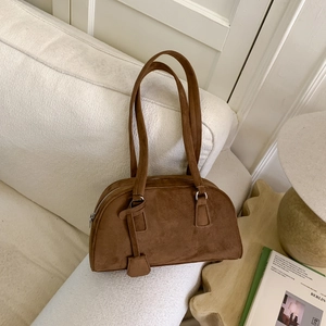Detailed view of brown matte Boston bag with long handles in a minimalist home setting