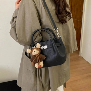 Detail of black pebbled leather bucket bag with silver twist lock and cute bear charm