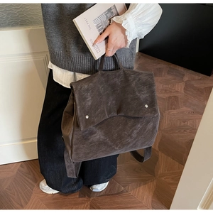 Detailed view of dark brown faux suede backpack with silver studs and top handle