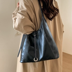 Detail of black tote bag featuring white contrast stitching and silver metal ring