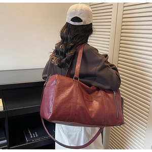 Gros plan du sac de sport bordeaux montrant la texture en similicuir et zip latéral