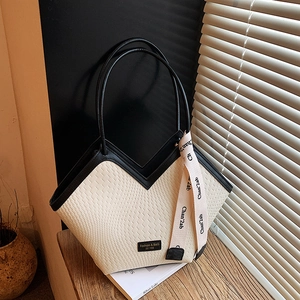 Close-up of woven beige leather tote with black trim and elegant decorative silk scarf